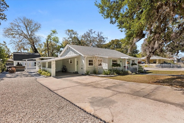 view of front of home with driveway, fence, roof with shingles, board and batten siding, and a carport