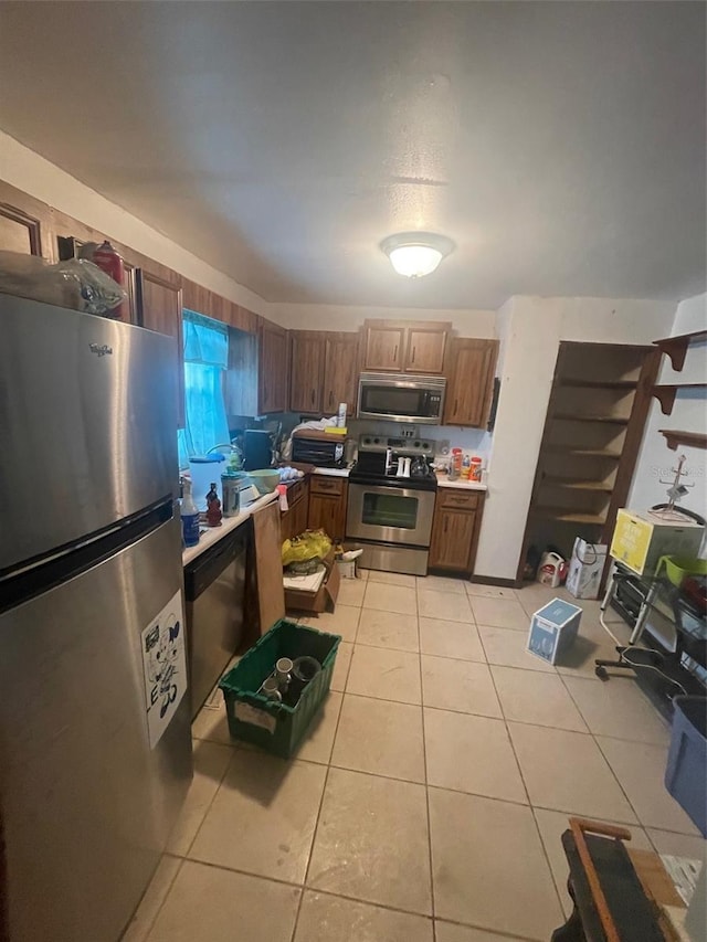 kitchen with appliances with stainless steel finishes, light tile patterned flooring, and light countertops