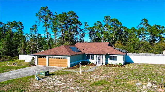 view of front facade with solar panels, a front lawn, fence, concrete driveway, and an attached garage