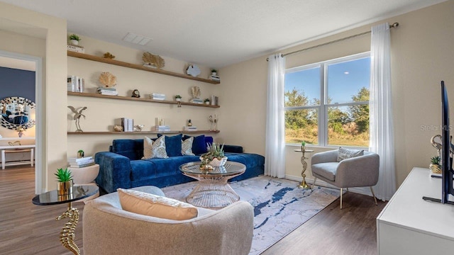 living area with visible vents and wood finished floors