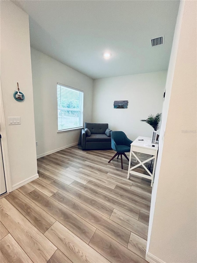 sitting room with light wood finished floors, visible vents, and baseboards