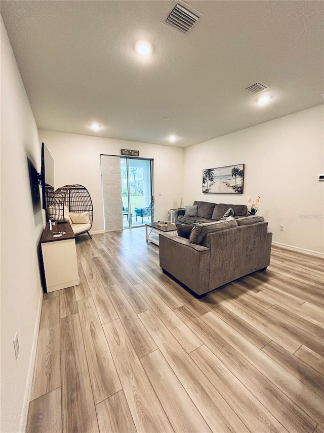 living area featuring visible vents, baseboards, and light wood-style flooring