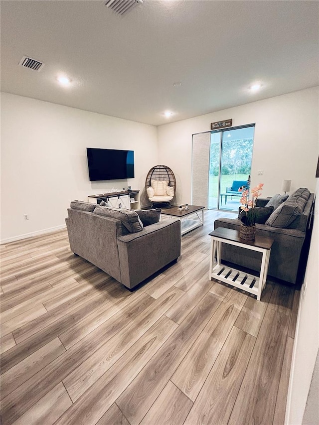 living area featuring visible vents, baseboards, and light wood finished floors