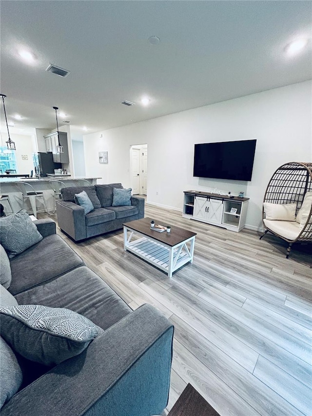 living area with baseboards, visible vents, and light wood finished floors