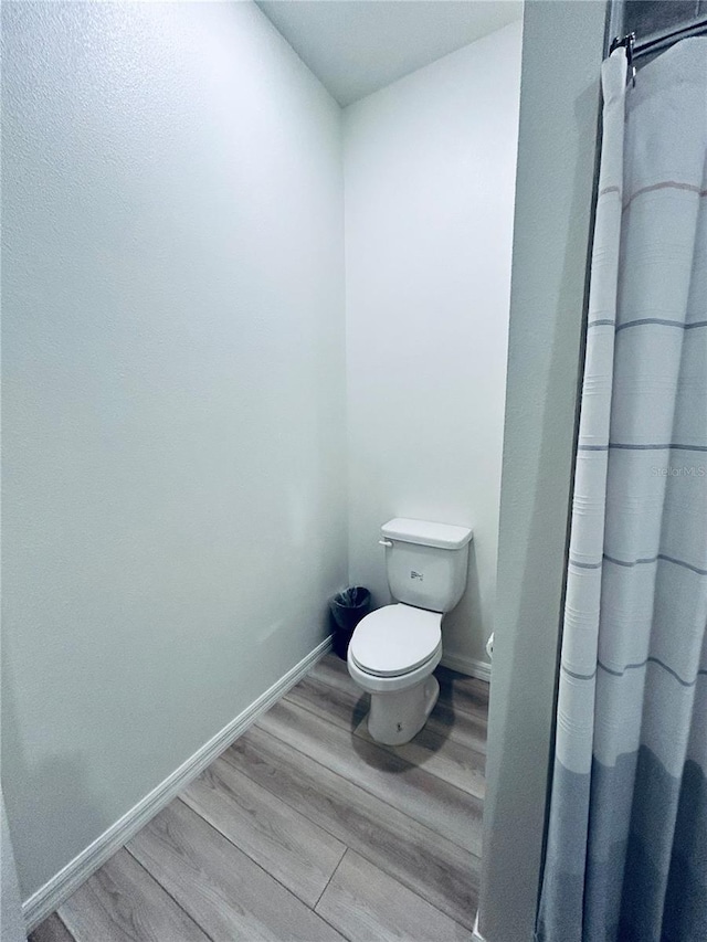 bathroom featuring baseboards, toilet, and wood finished floors