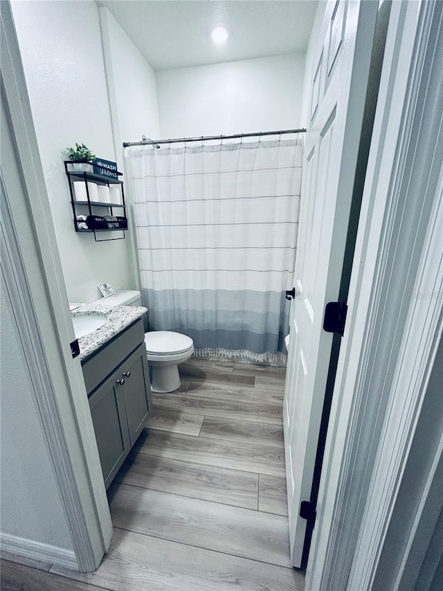 full bathroom featuring toilet, curtained shower, vanity, and wood finished floors