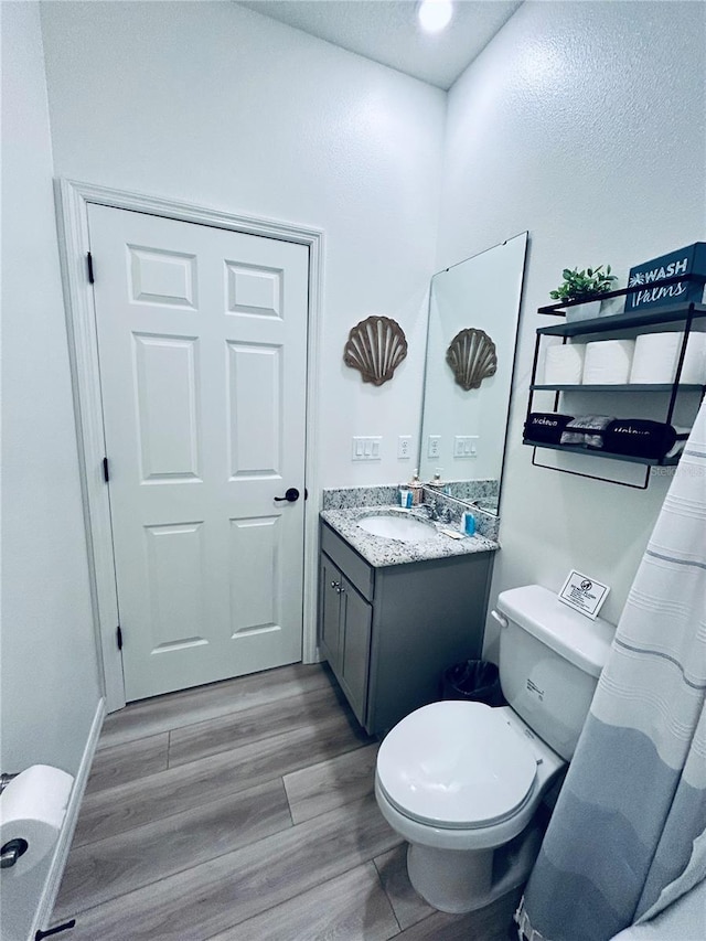 full bathroom with toilet, wood finished floors, and vanity