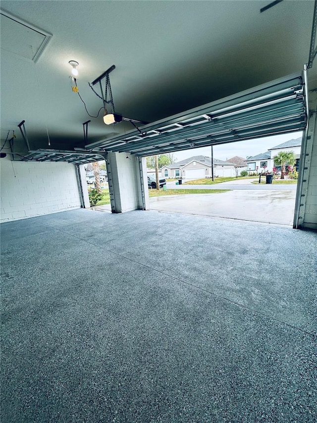 garage featuring a residential view, concrete block wall, and a garage door opener