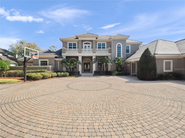 mediterranean / spanish-style home with stucco siding, a balcony, and curved driveway