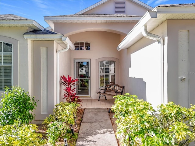 view of exterior entry with covered porch and stucco siding