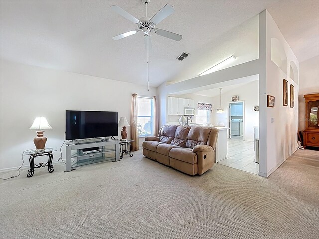 living room with a ceiling fan, visible vents, washer / clothes dryer, a textured ceiling, and light colored carpet