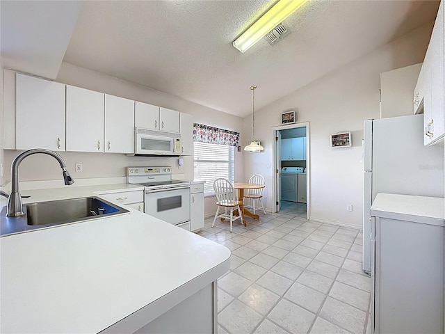 kitchen featuring white appliances, visible vents, lofted ceiling, a sink, and independent washer and dryer