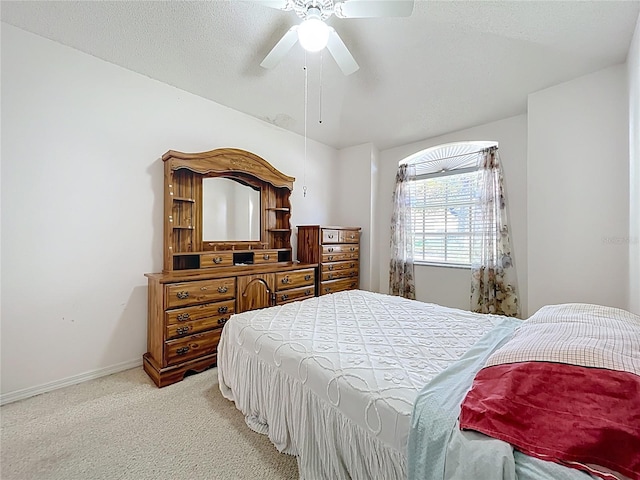 bedroom featuring baseboards, light colored carpet, ceiling fan, and a textured ceiling