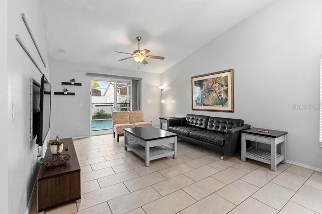 living area featuring vaulted ceiling, light tile patterned flooring, and a ceiling fan