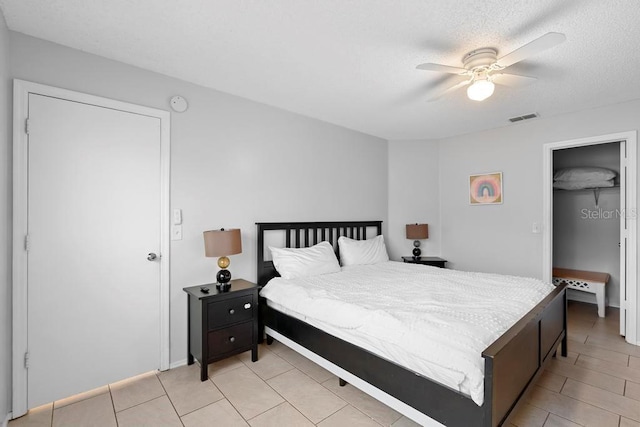 bedroom featuring visible vents, a textured ceiling, ceiling fan, and a spacious closet