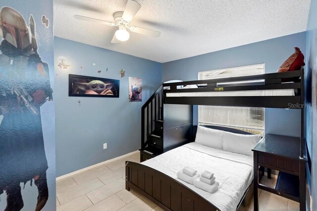 tiled bedroom with baseboards, a textured ceiling, and ceiling fan