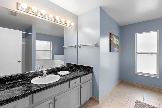 bathroom featuring vanity, baseboards, visible vents, a tub, and tile patterned flooring