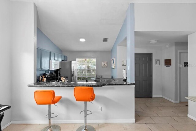 kitchen featuring visible vents, a kitchen breakfast bar, stainless steel appliances, dark stone counters, and a peninsula