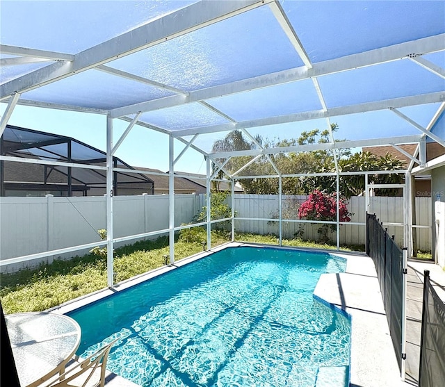 view of pool with glass enclosure, a patio, a fenced backyard, and a fenced in pool