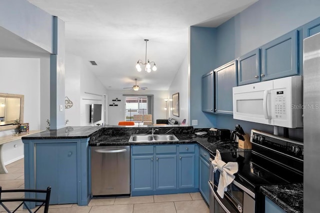 kitchen featuring light tile patterned floors, a peninsula, a sink, appliances with stainless steel finishes, and blue cabinets