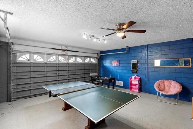 playroom with concrete block wall, a garage, concrete floors, and a textured ceiling