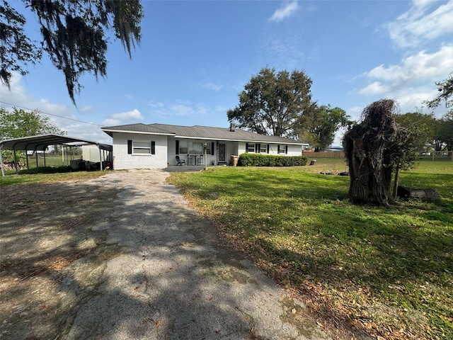 ranch-style home with a detached carport, brick siding, a front lawn, aphalt driveway, and a porch