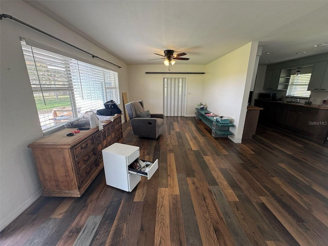 living area with baseboards, dark wood-style floors, and a ceiling fan