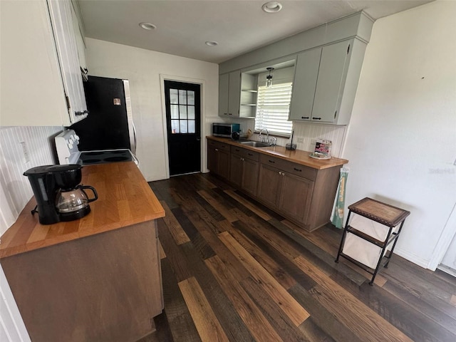 kitchen with stainless steel microwave, dark wood-style floors, electric range, refrigerator, and a sink