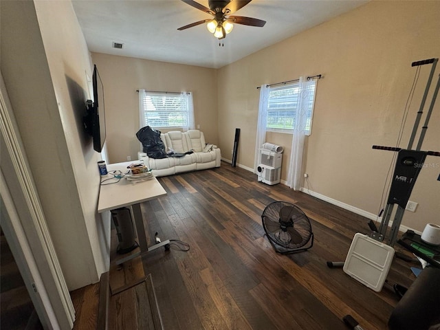 living area featuring a wealth of natural light, visible vents, heating unit, and dark wood-type flooring