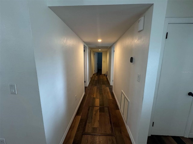 corridor with dark wood-type flooring, baseboards, and visible vents