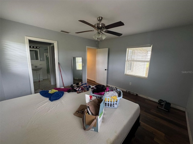 bedroom with visible vents, a ceiling fan, ensuite bathroom, wood finished floors, and baseboards