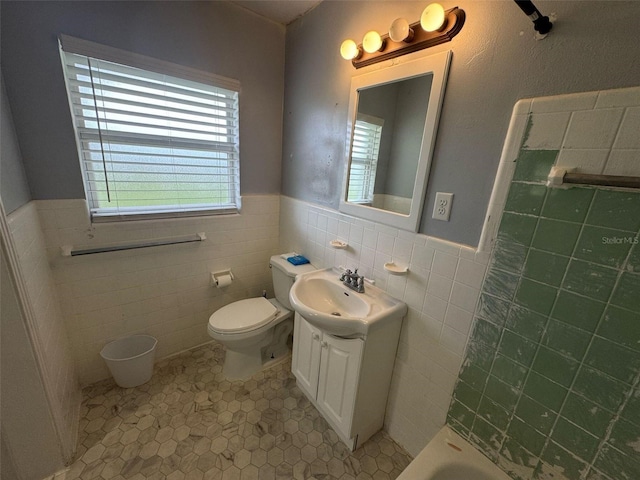 full bath with vanity, tile walls, toilet, and wainscoting