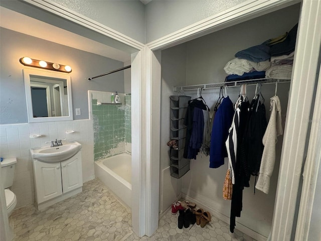 bathroom with vanity, bathtub / shower combination, tile walls, toilet, and tile patterned floors