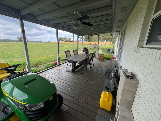 wooden deck featuring a lawn, ceiling fan, and a rural view