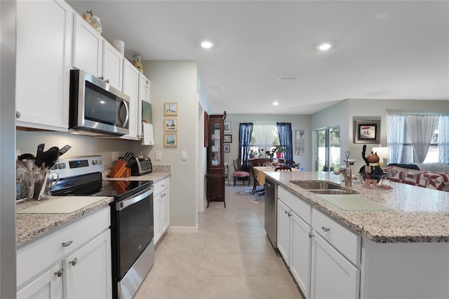 kitchen featuring recessed lighting, a sink, stainless steel appliances, white cabinetry, and open floor plan