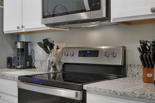 kitchen featuring light stone counters, appliances with stainless steel finishes, and white cabinetry