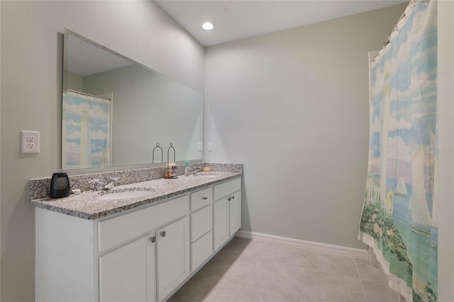 full bath with a sink, baseboards, double vanity, and tile patterned floors