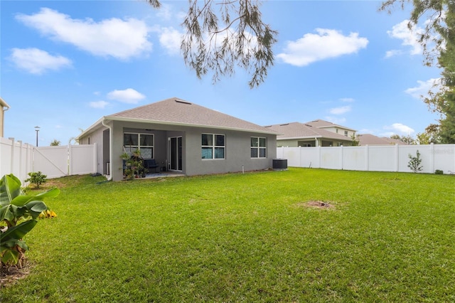 rear view of property with a fenced backyard, a lawn, central AC, and stucco siding