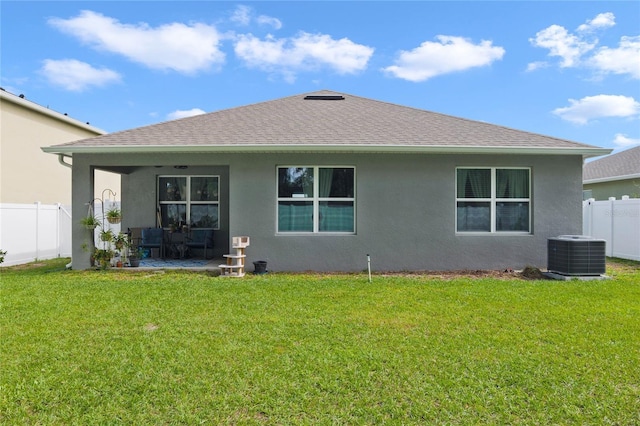 rear view of house featuring a yard, central AC, and stucco siding