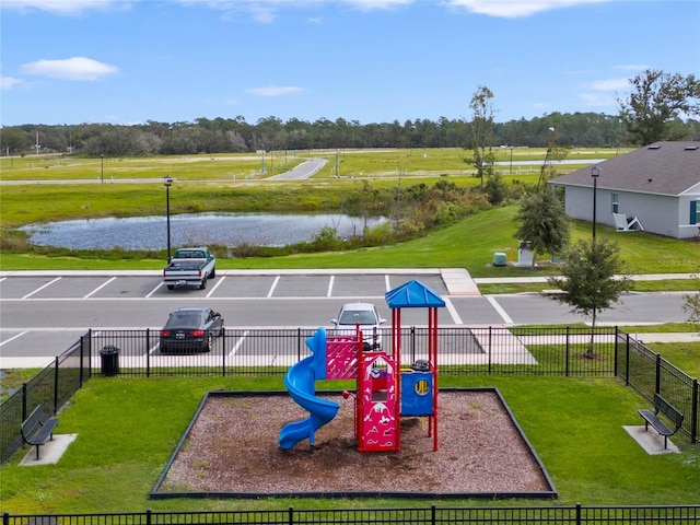 communal playground featuring a water view, a yard, and fence