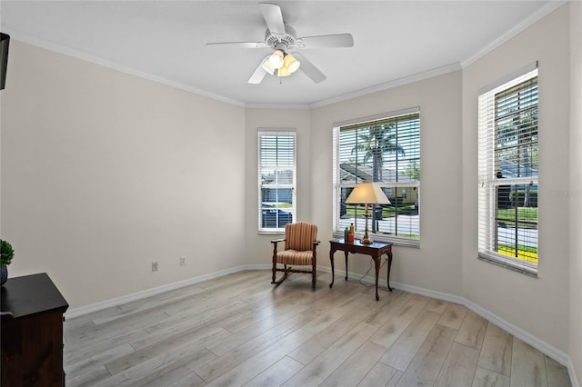 sitting room featuring a ceiling fan, baseboards, light wood-style floors, and crown molding