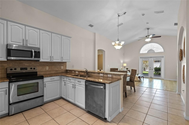 kitchen with a sink, a peninsula, light tile patterned floors, and stainless steel appliances