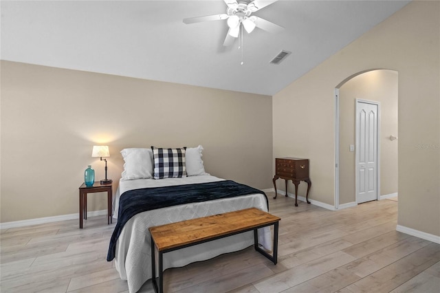 bedroom featuring light wood-type flooring, visible vents, arched walkways, and lofted ceiling