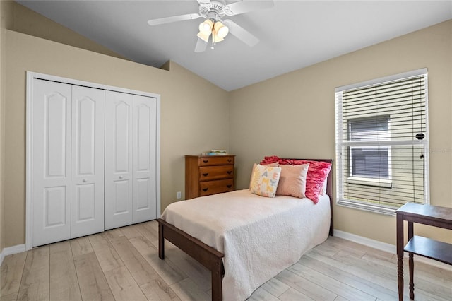 bedroom featuring a closet, multiple windows, wood finished floors, and vaulted ceiling