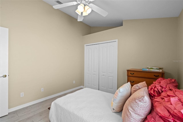 bedroom with a closet, lofted ceiling, baseboards, and light wood-style flooring