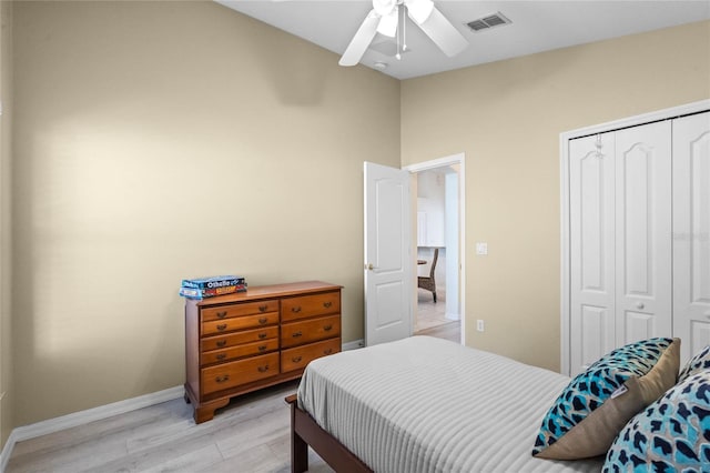 bedroom featuring baseboards, visible vents, light wood-style flooring, ceiling fan, and a closet