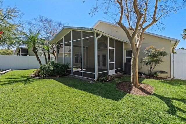 rear view of property with a yard, a sunroom, and fence