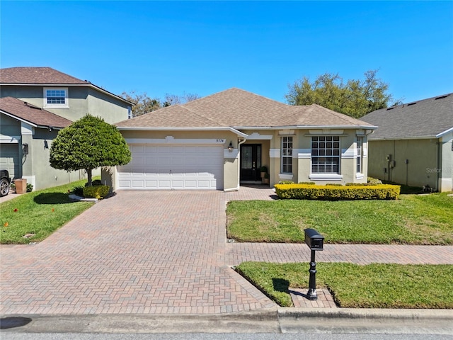 view of front facade with stucco siding, decorative driveway, a front yard, a shingled roof, and a garage