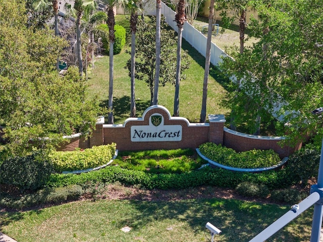 community / neighborhood sign with a lawn and fence