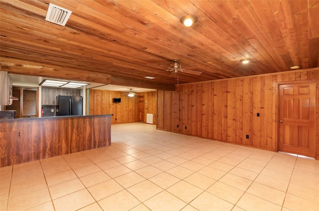 unfurnished living room featuring light tile patterned flooring, visible vents, wood ceiling, and wooden walls